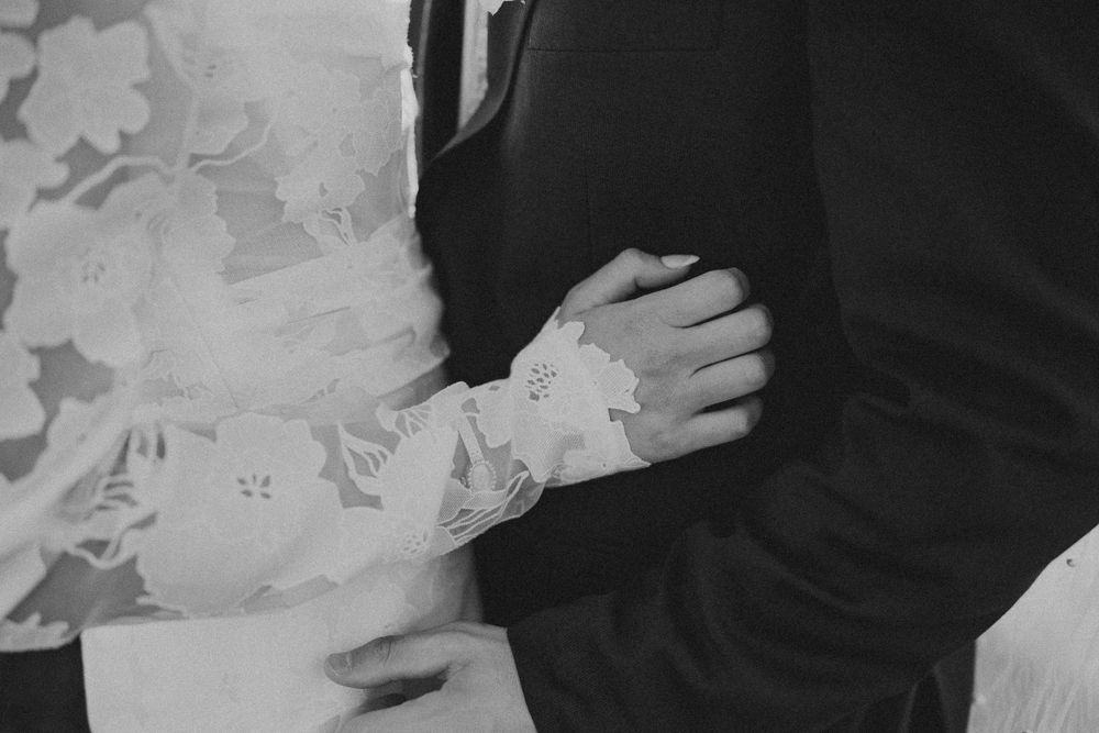 Close-up black and white shot of lace wedding dress details and formal attire.