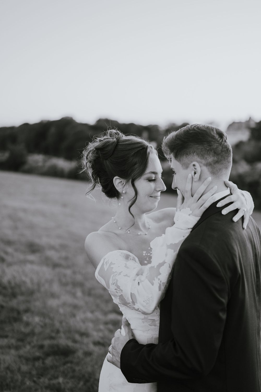 A black and white intimate portrait of newlyweds sharing a tender moment outdoors.