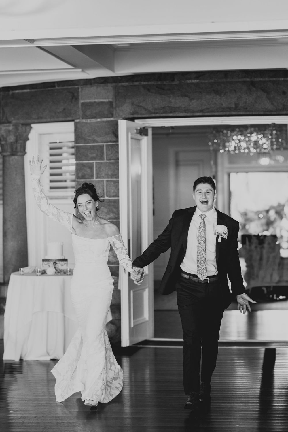 A black and white photo of newlyweds making their grand entrance at their reception.