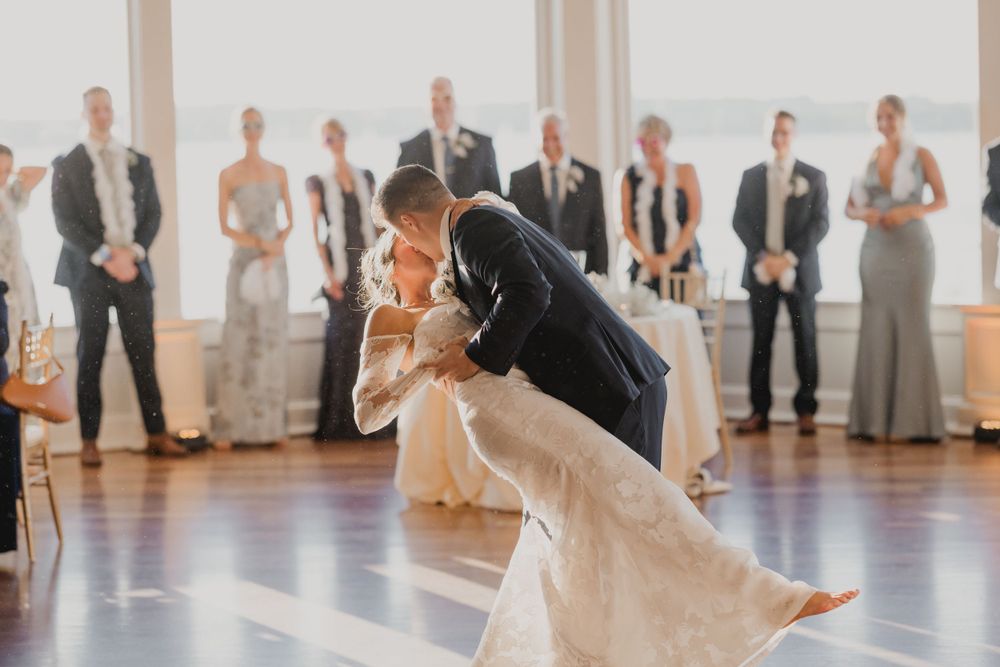 A dramatic dip during the newlyweds' first dance with guests watching in the background.