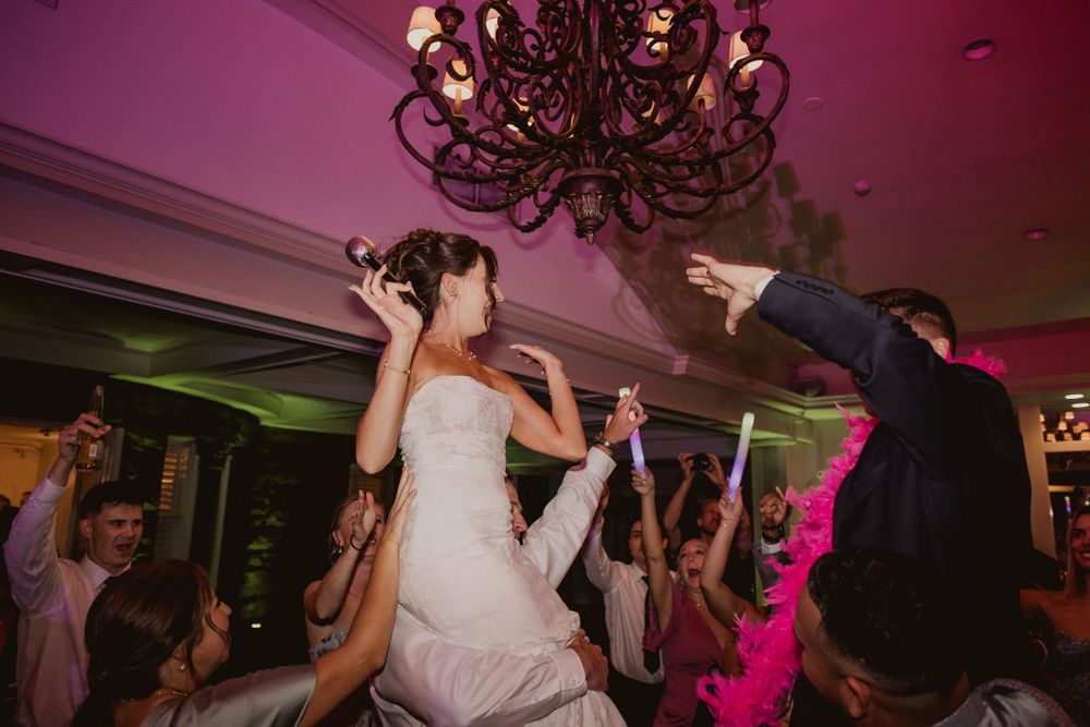 Wedding reception dance floor illuminated with dramatic purple and pink lighting effects.