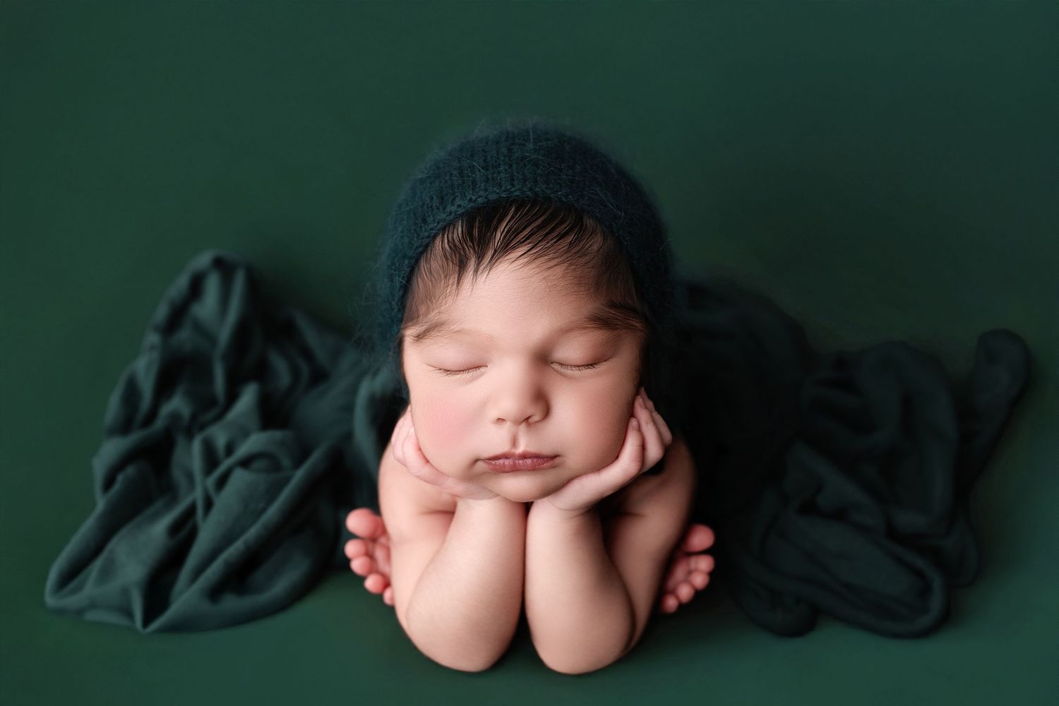 Newborn baby wrapped in soft blue swaddle sleeping peacefully in round bowl with cream colored blanket background.