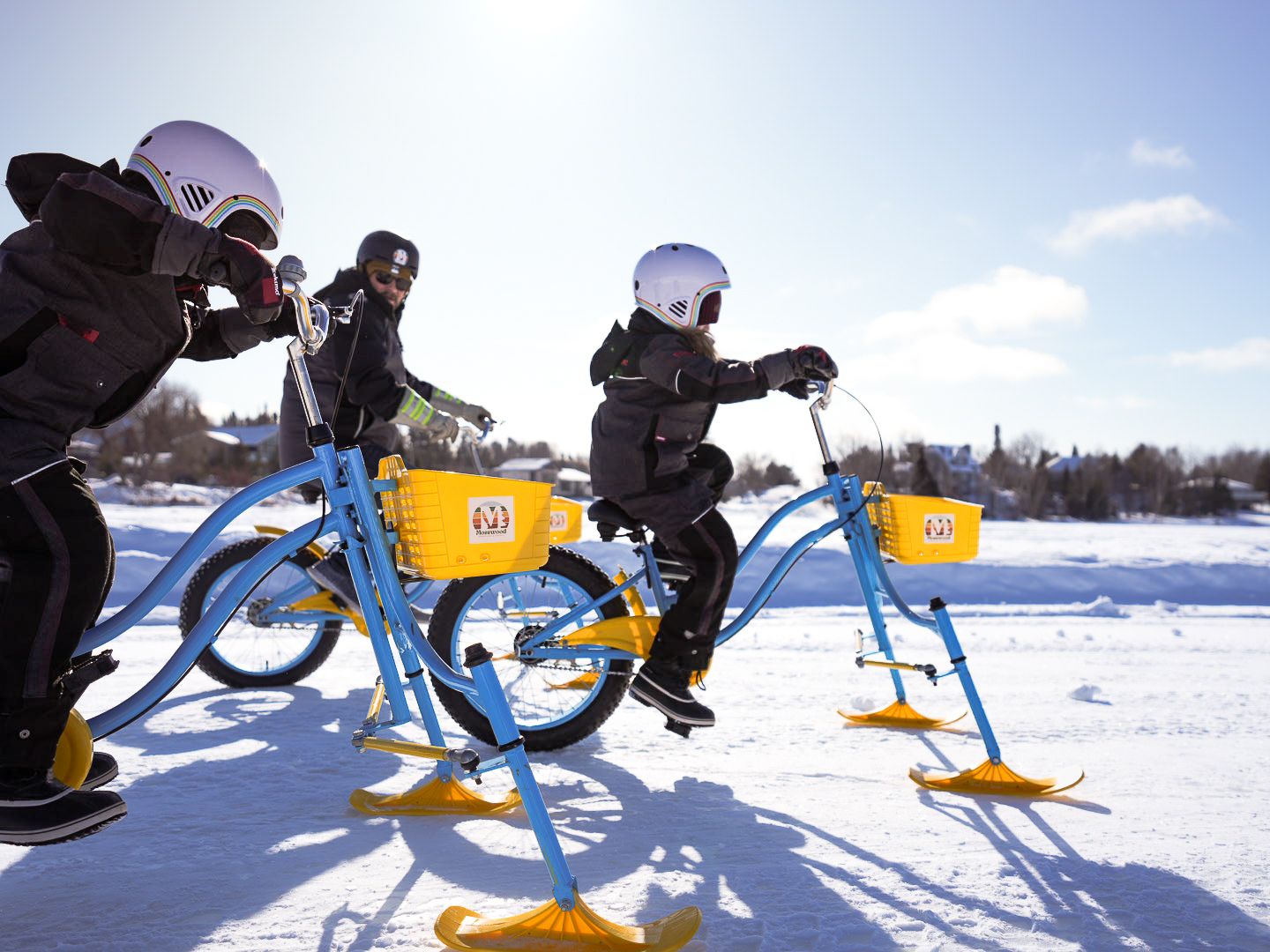 Snow bikes lined up on frozen lake with winter recreation equipment.