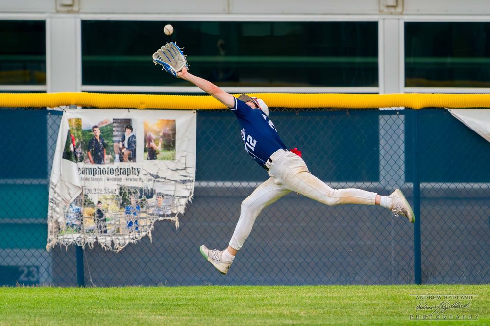 Baseball outfielder making a spectacular diving catch near the warning track.