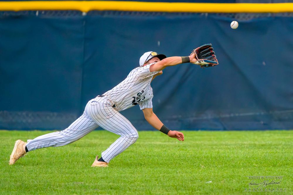 Outfielder diving horizontally to make a spectacular catch on the baseball field.