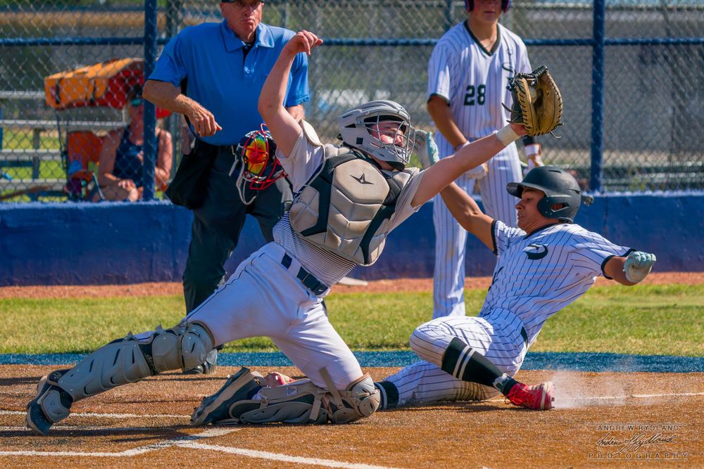 Baseball players colliding at home plate during an intense play at the ballpark.