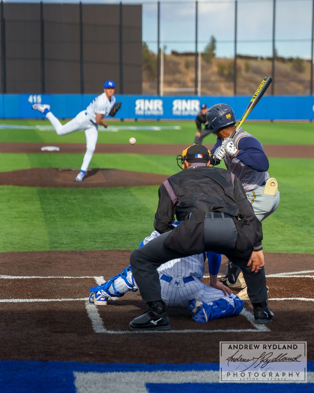 Baseball game action at home plate with pitcher, batter, catcher and umpire.