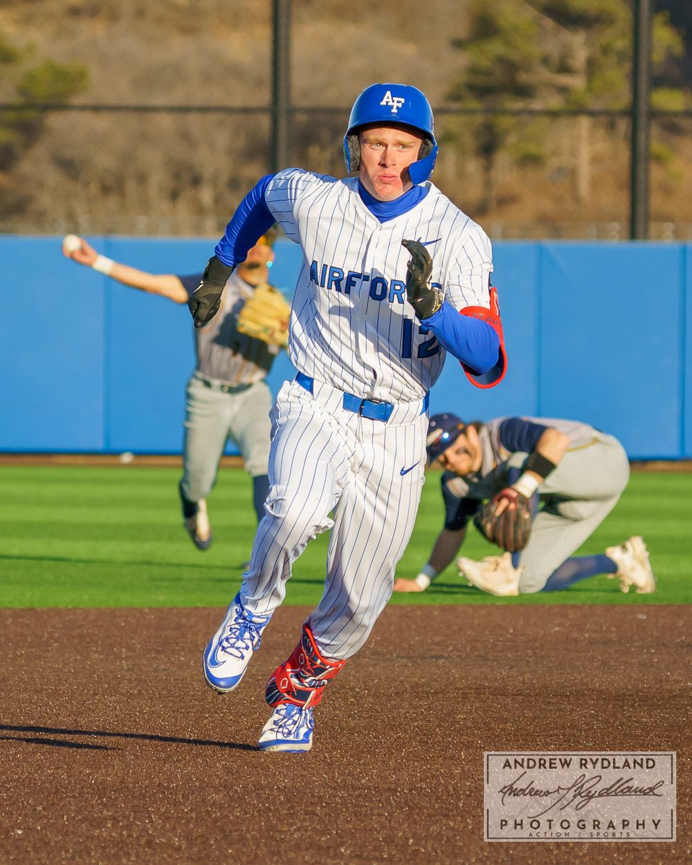 Baseball player sprinting down baseline in pinstriped uniform during game action.