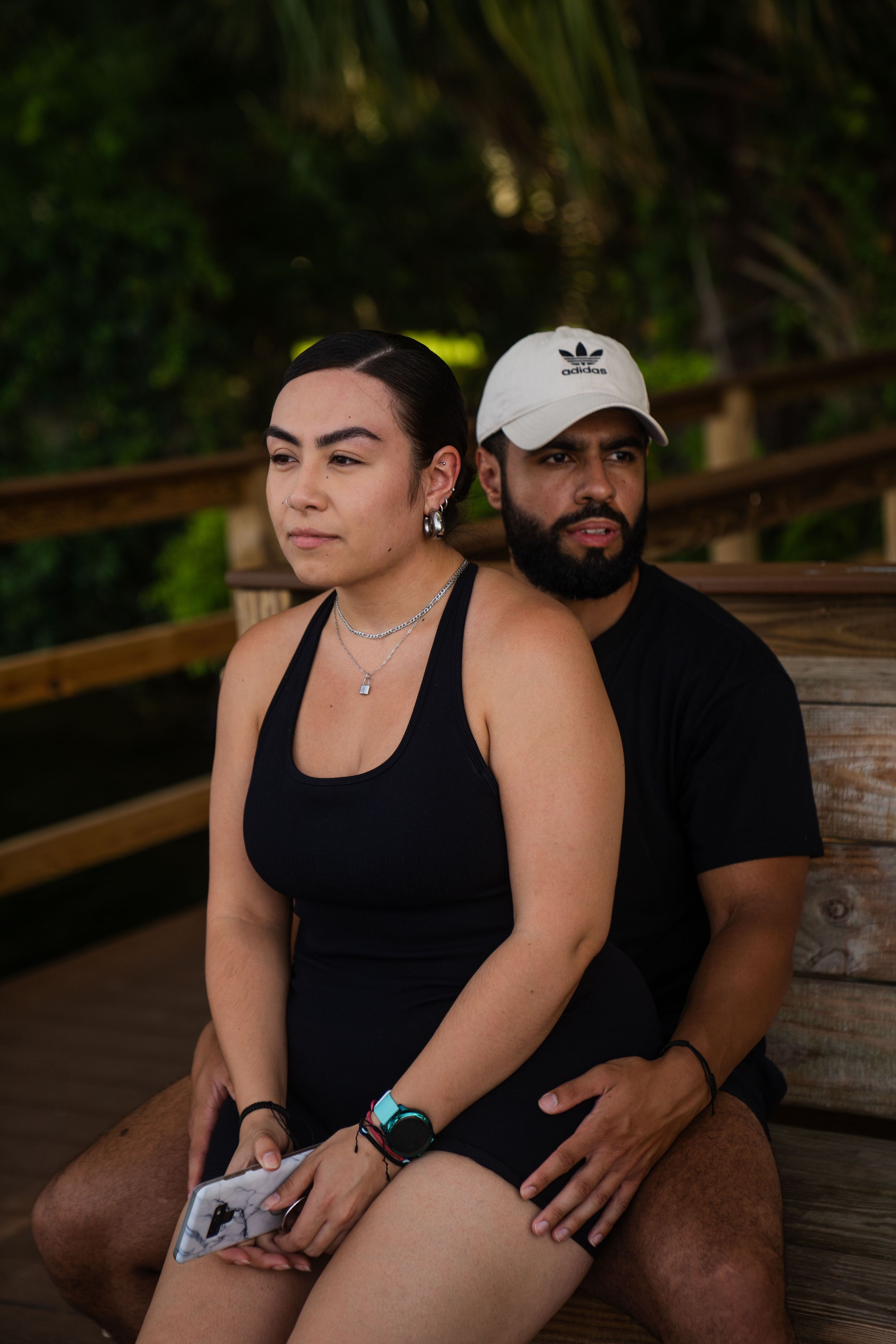Couple sitting close together on wooden bench in casual athletic wear.