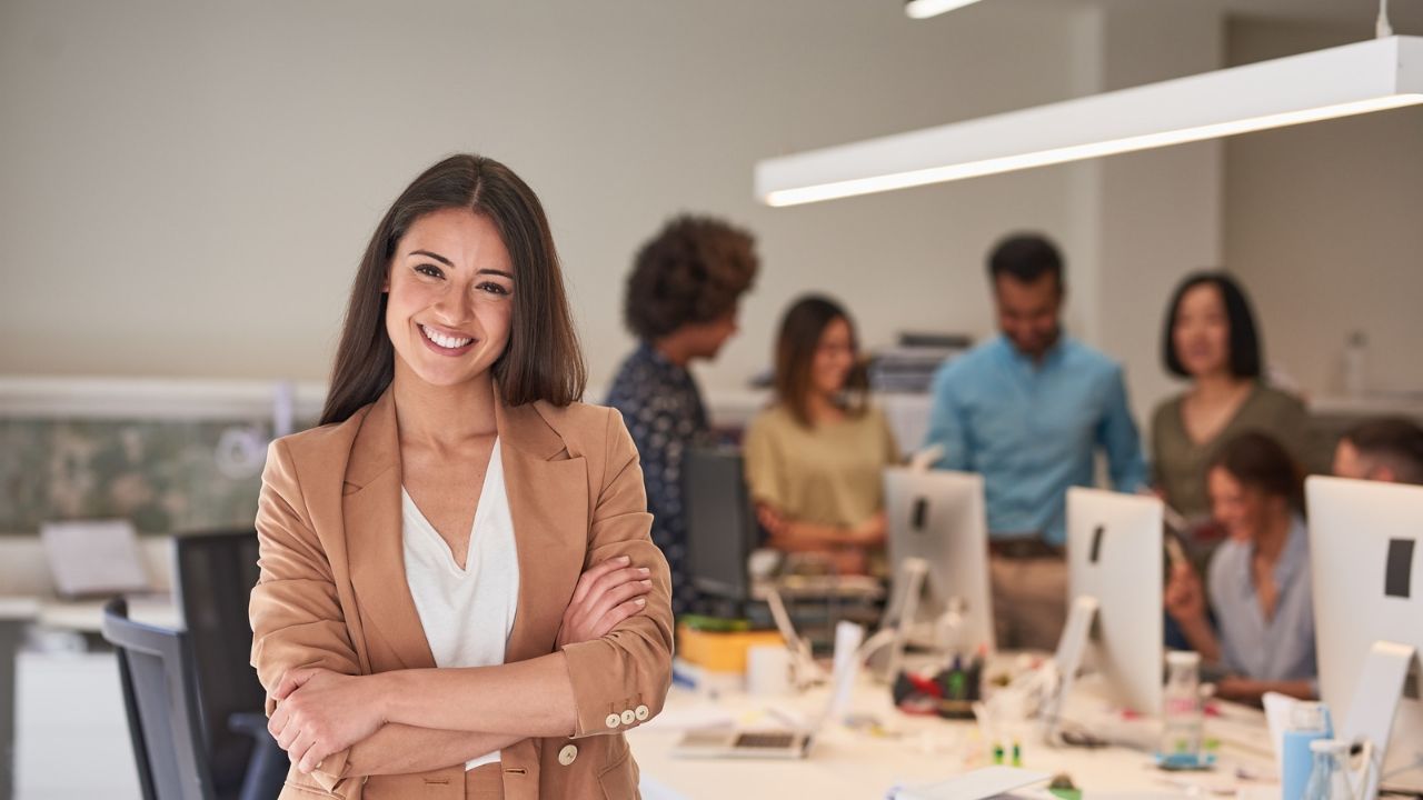 A professional black lady with a warm smile in the office with folded arms