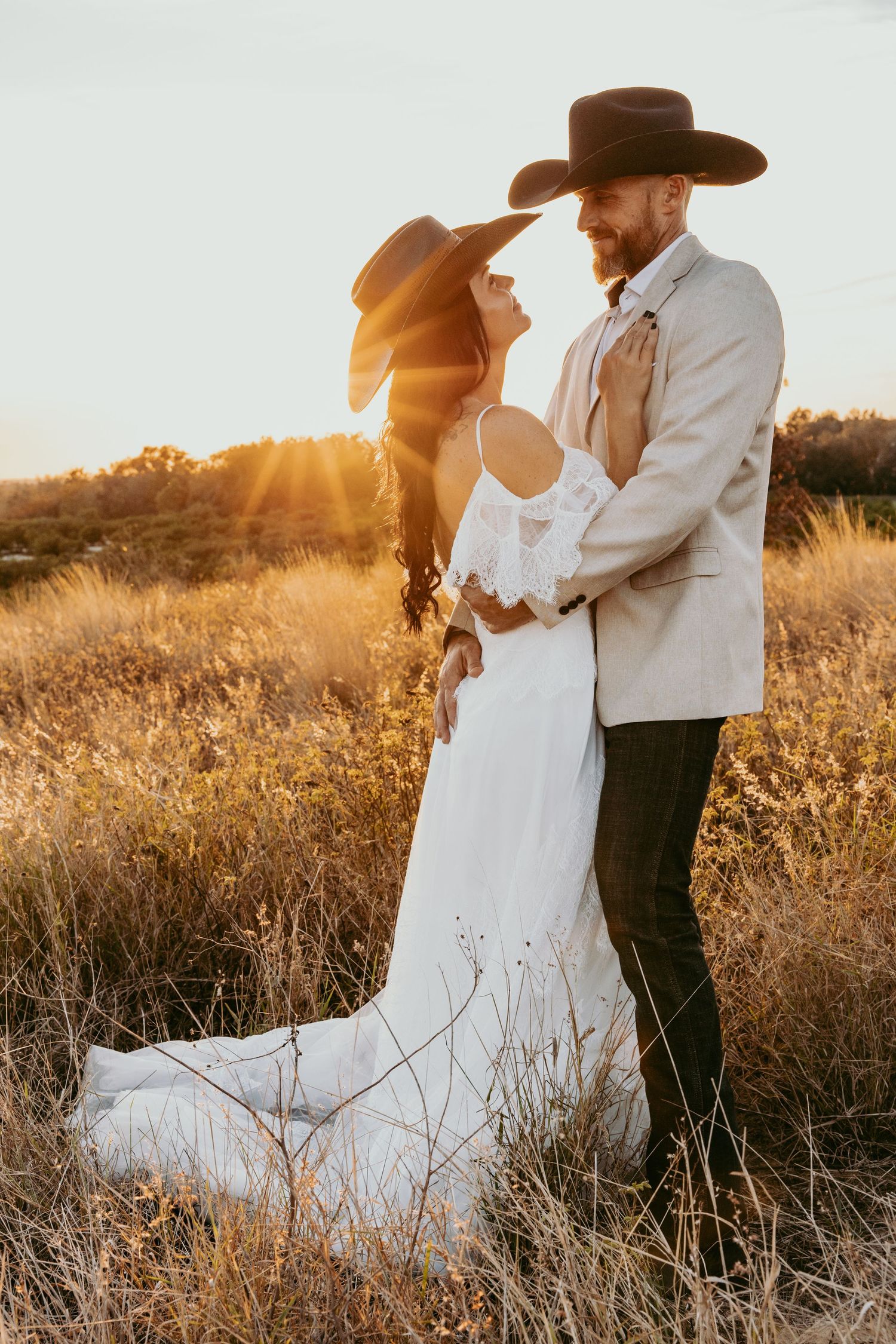 Western style bride and groom embrace in golden sunset light among tall grasses wearing cowboy hats at Bok Tower lake Wales