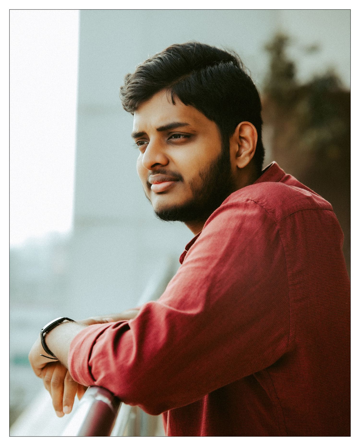 Person in a red sweater looking thoughtfully to the side in natural lighting.