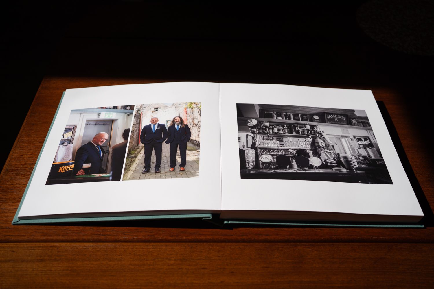 An open photo album displaying black and white and color photographs on a wooden table.