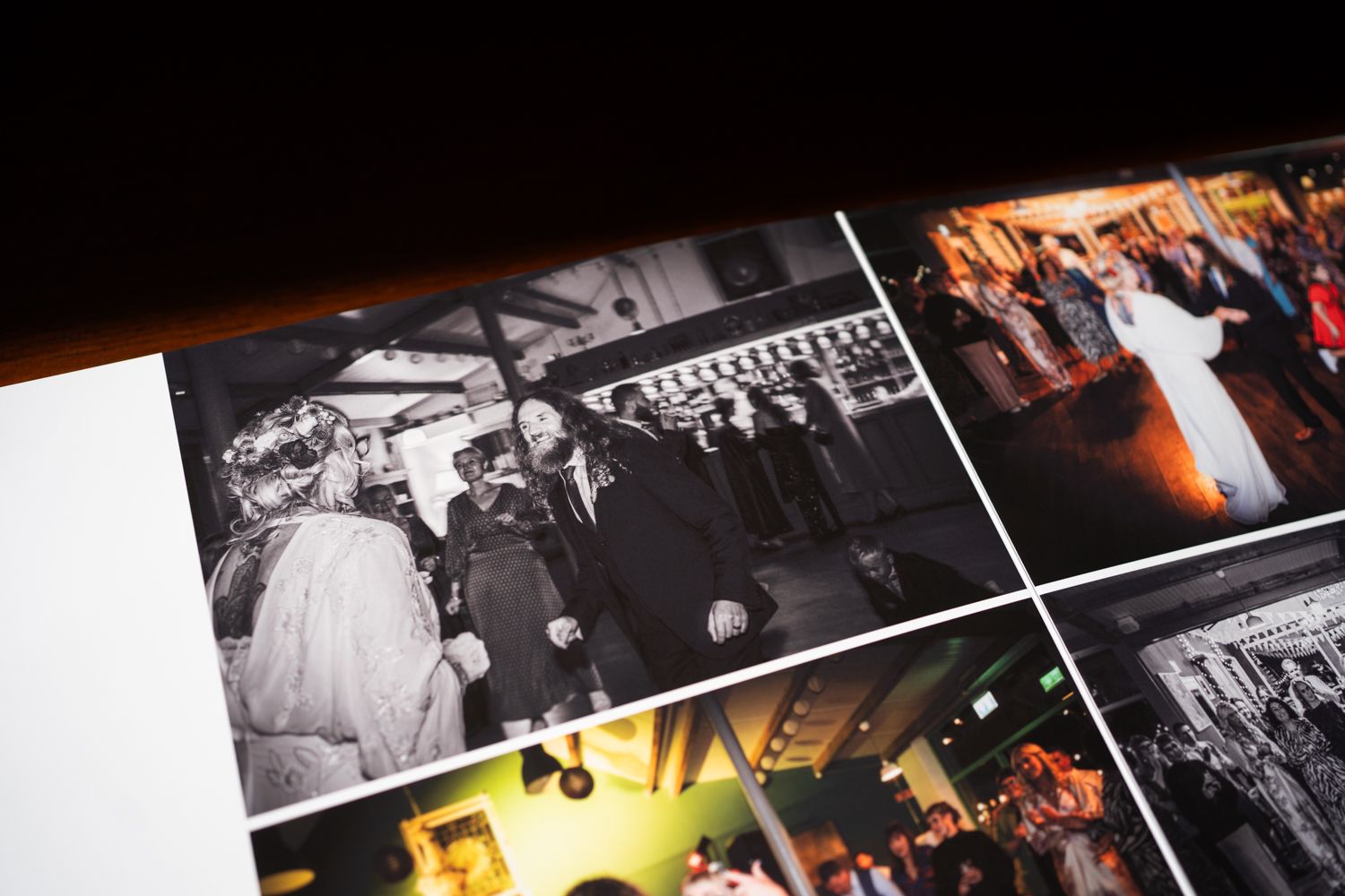 A close-up view of a wedding photo album showing black and white reception photos alongside color celebration images.