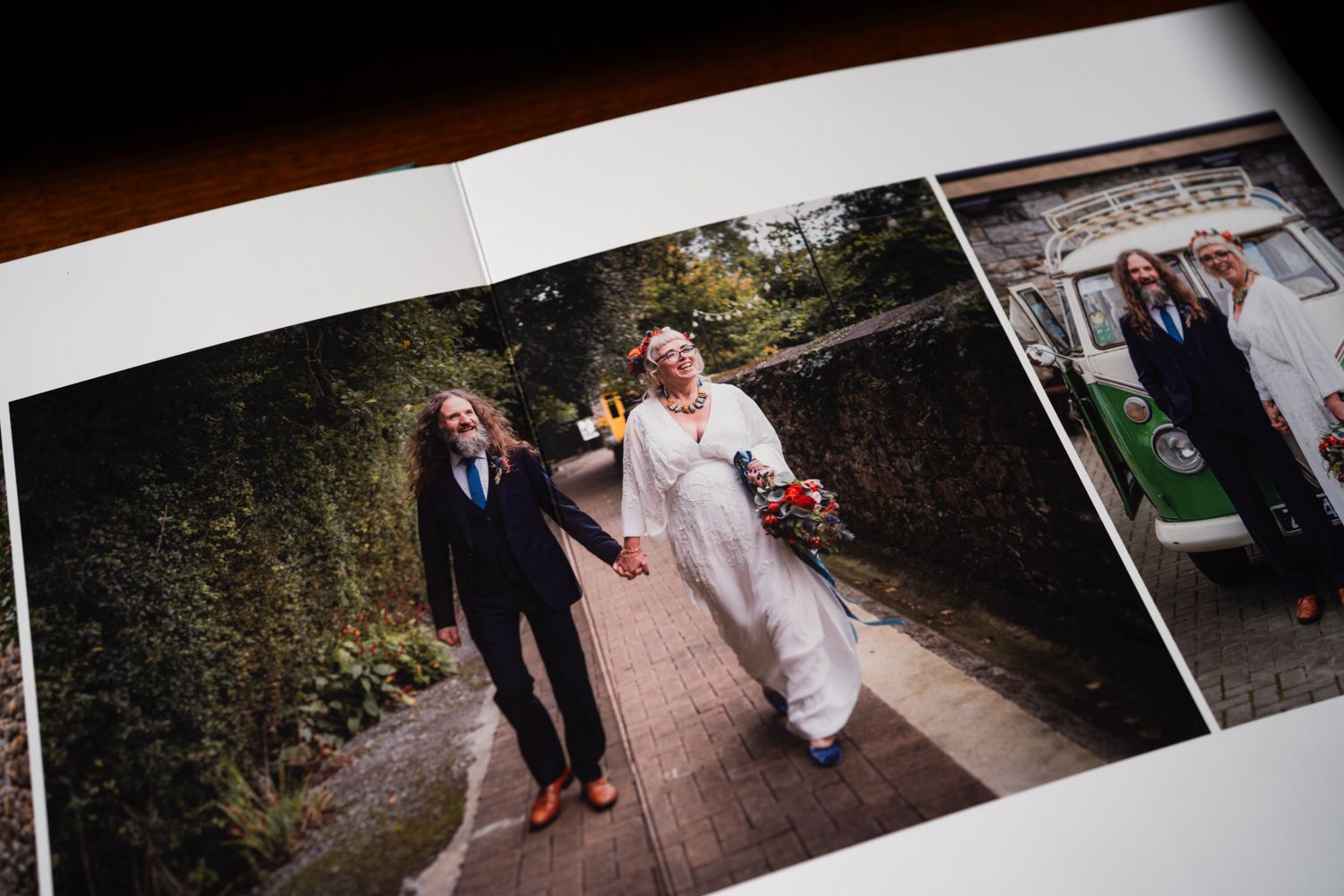 Two people walk hand in hand down a garden pathway, one in white dress with a bouquet and one in dark suit.
