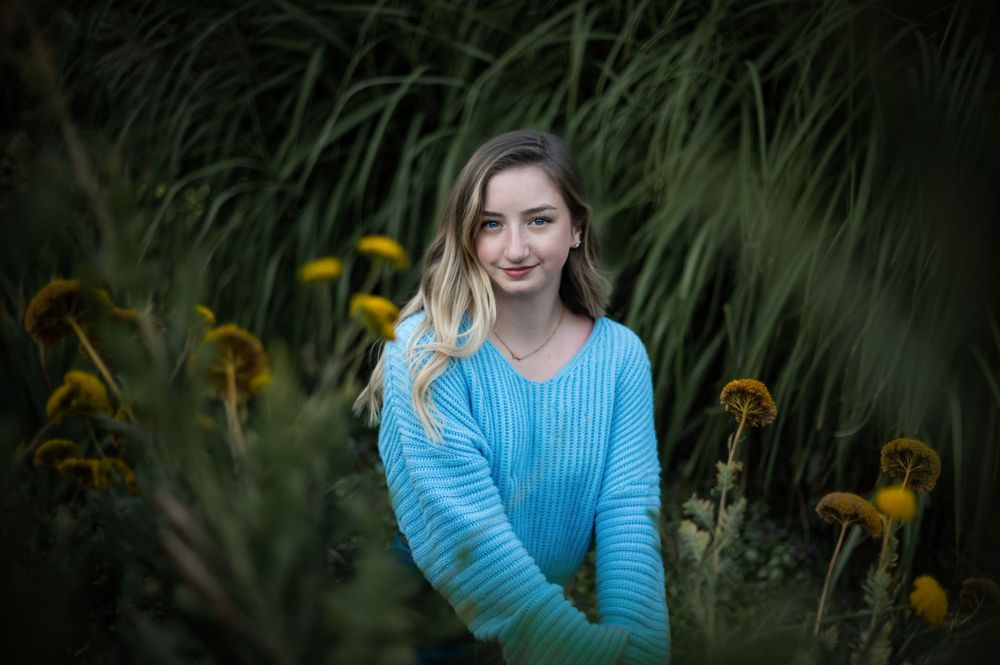 A high school senior taking a portrait in a dreamy flower garden at manito park in spokane washington. By Jessica Rae Photography.