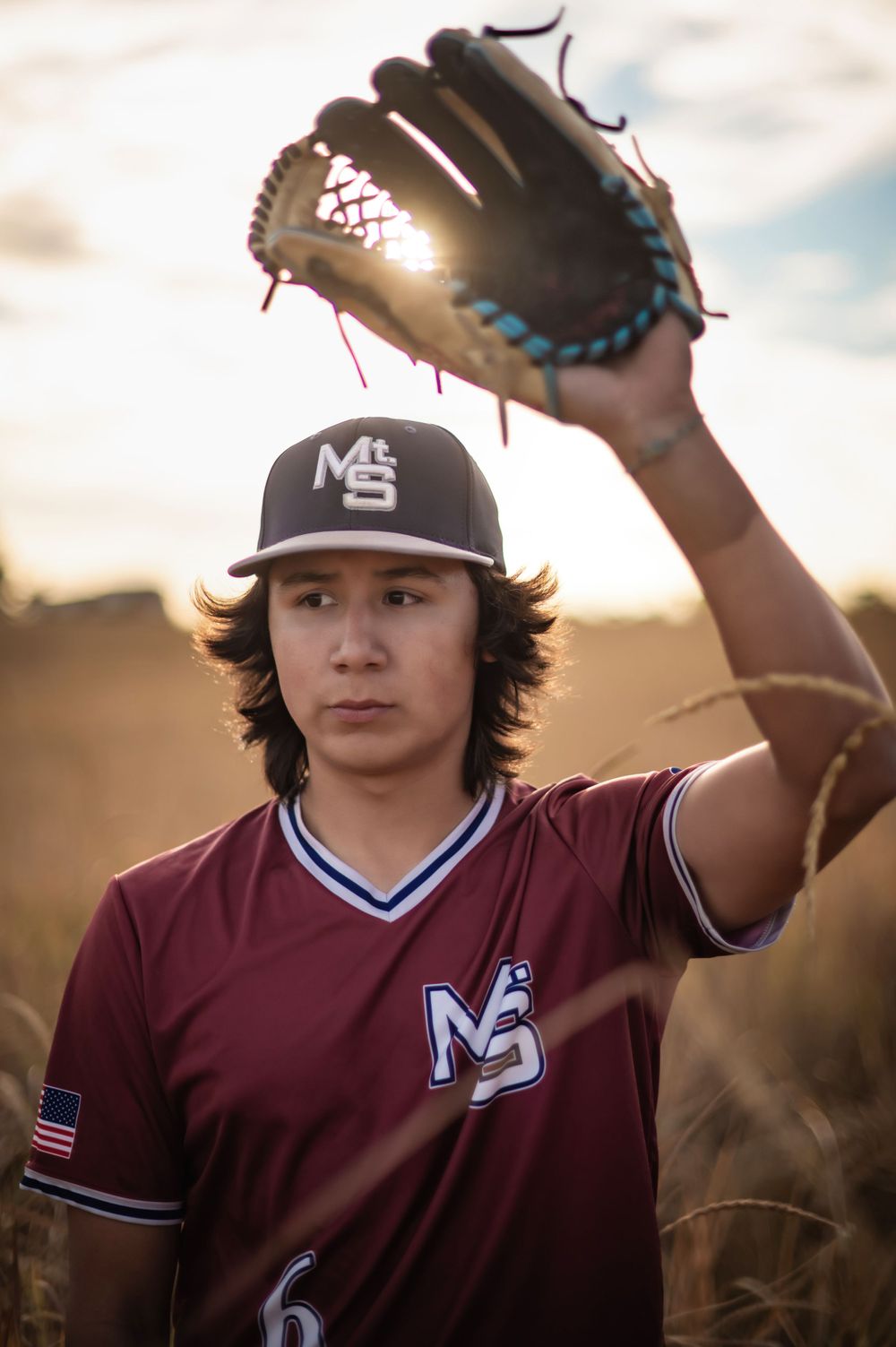 A high school senior portrait in his baseball uniform and glove during golden hour in Spokane Washington. By Jessica Rae Photography.