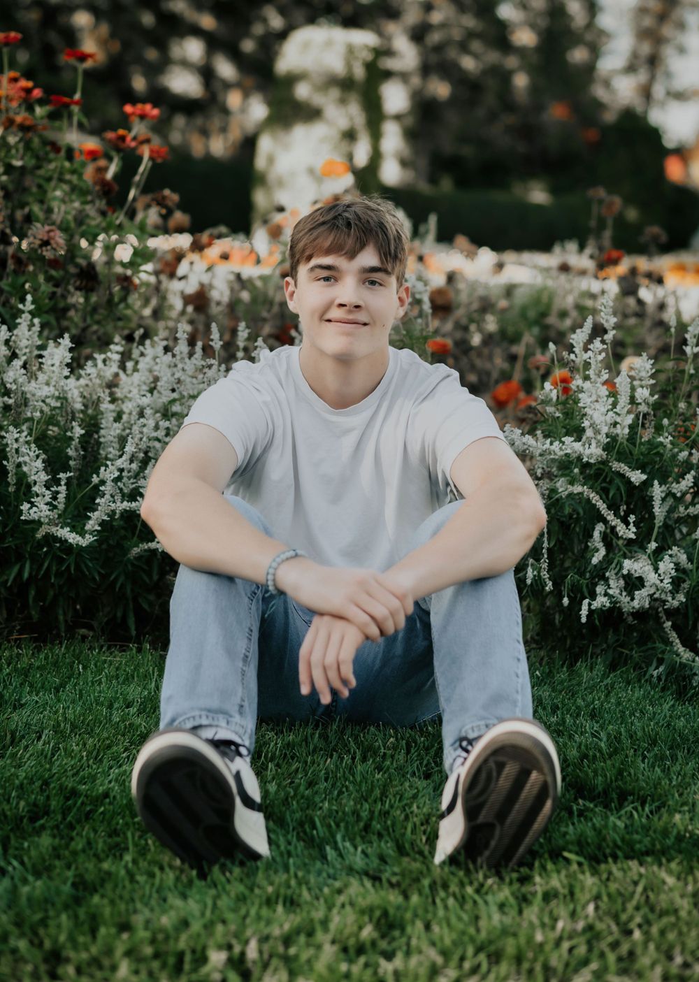 a high school senior sitting in the grass at manito park for his senior portrait session in spokane washington. By Jessica Rae Photography.