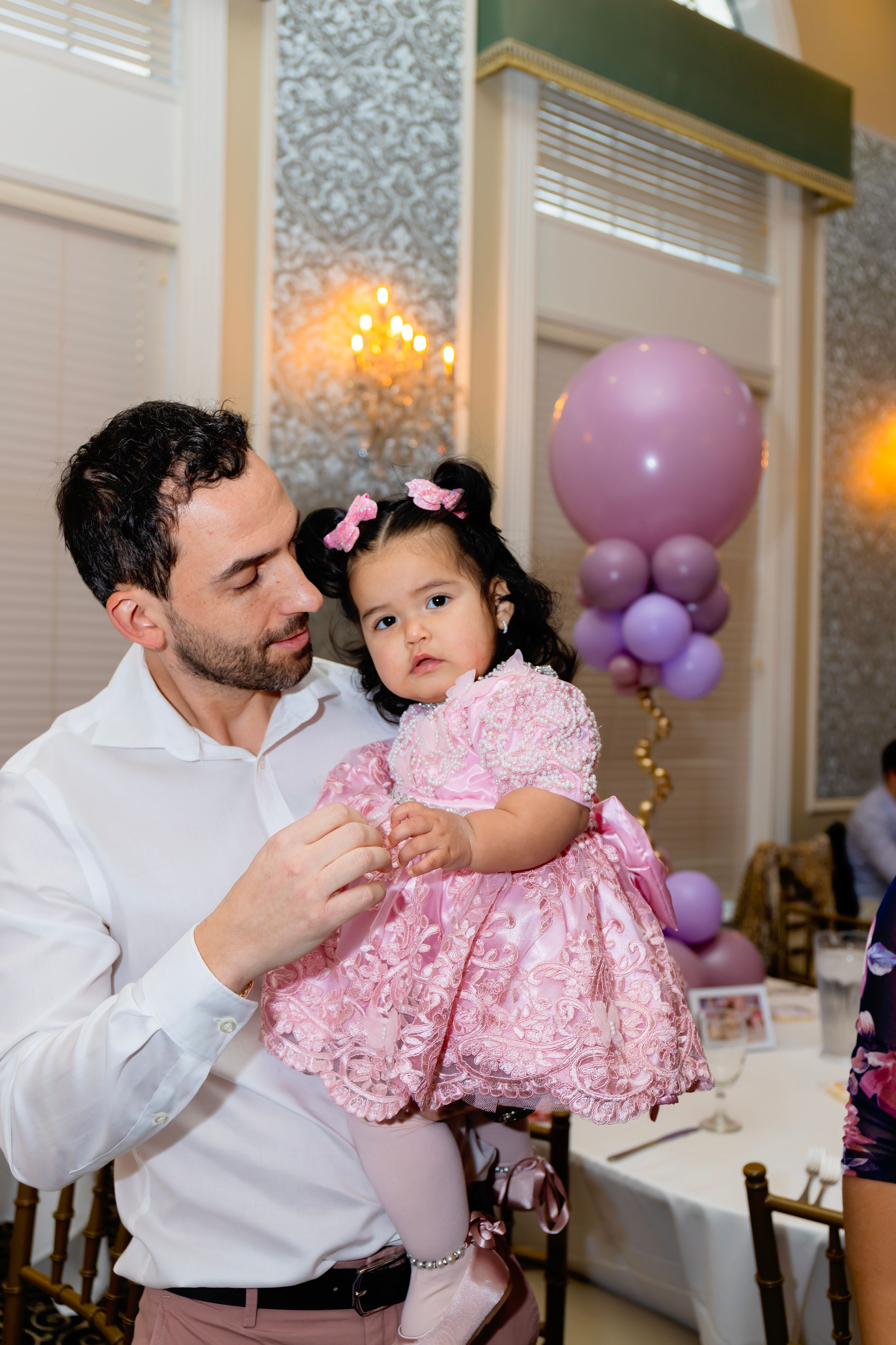 A special celebration moment features pink decorations and balloons at an indoor party venue.