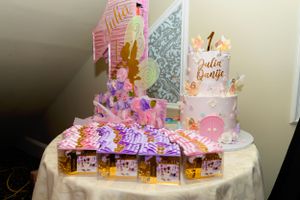 First birthday party decorations with pink and gold theme featuring a white cake and illuminated display table.