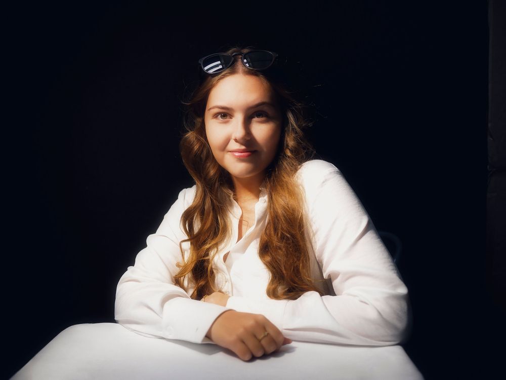 A series of professional studio portraits against a dark background shows a woman in a white sweater in various poses.