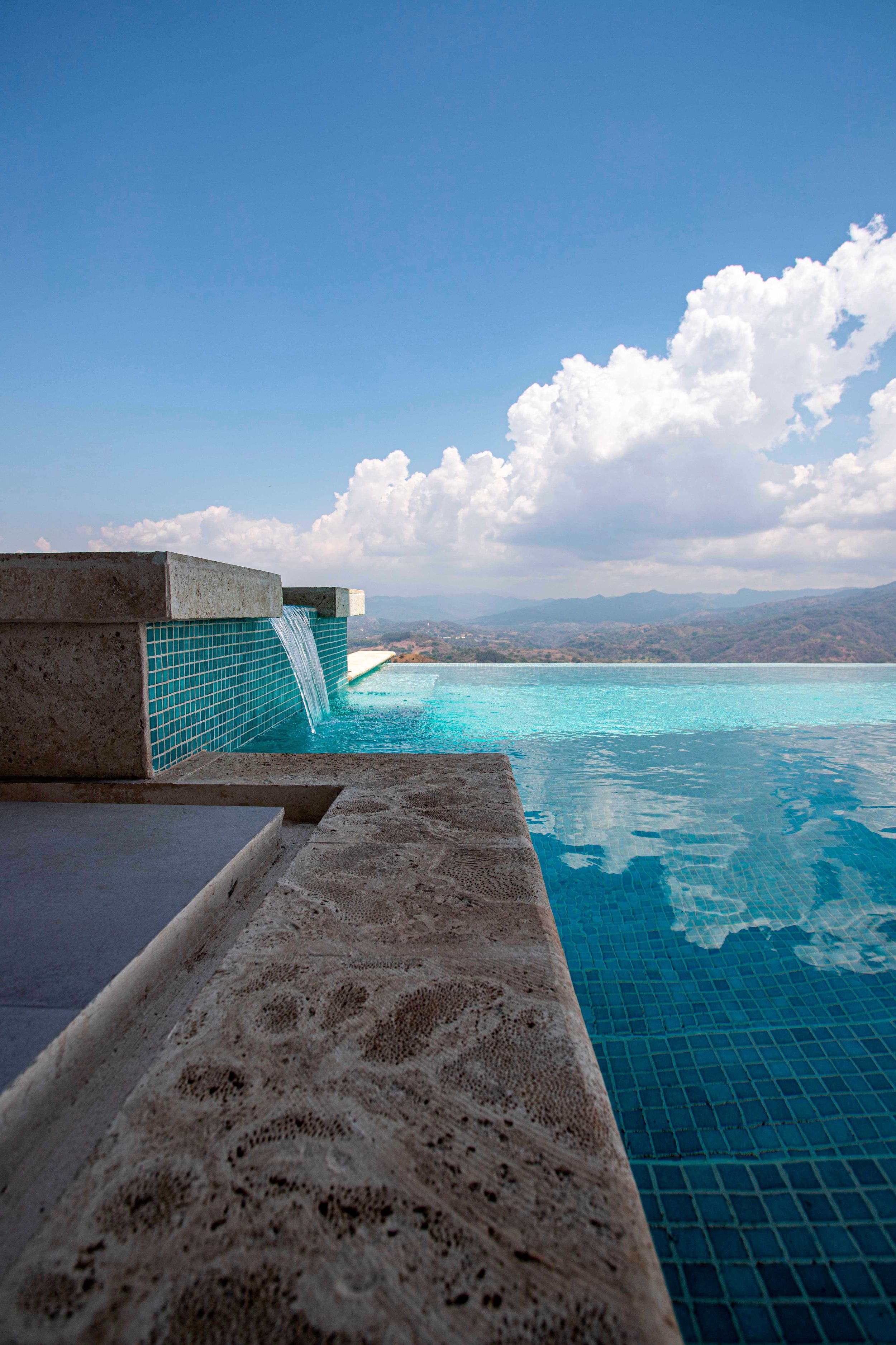 Infinity pool with breathtaking views of the rolling hills and mountains of Atenas, Costa Rica, under a clear blue sky