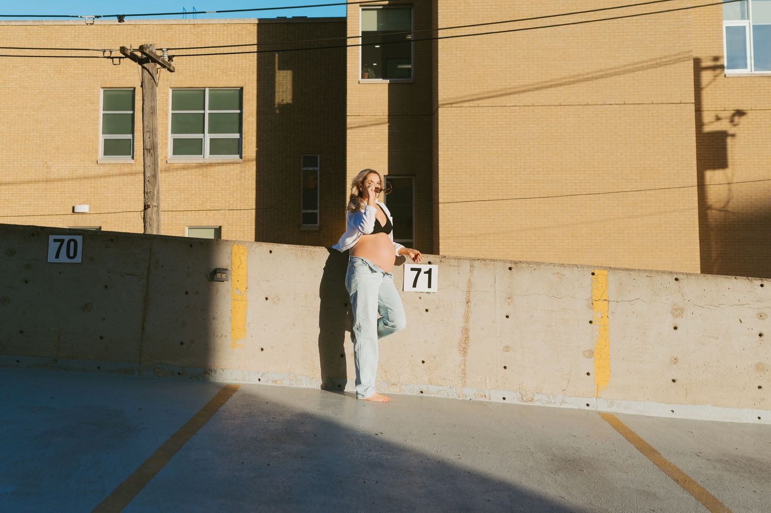 A casual outdoor photoshoot against a beige concrete wall in an urban setting.