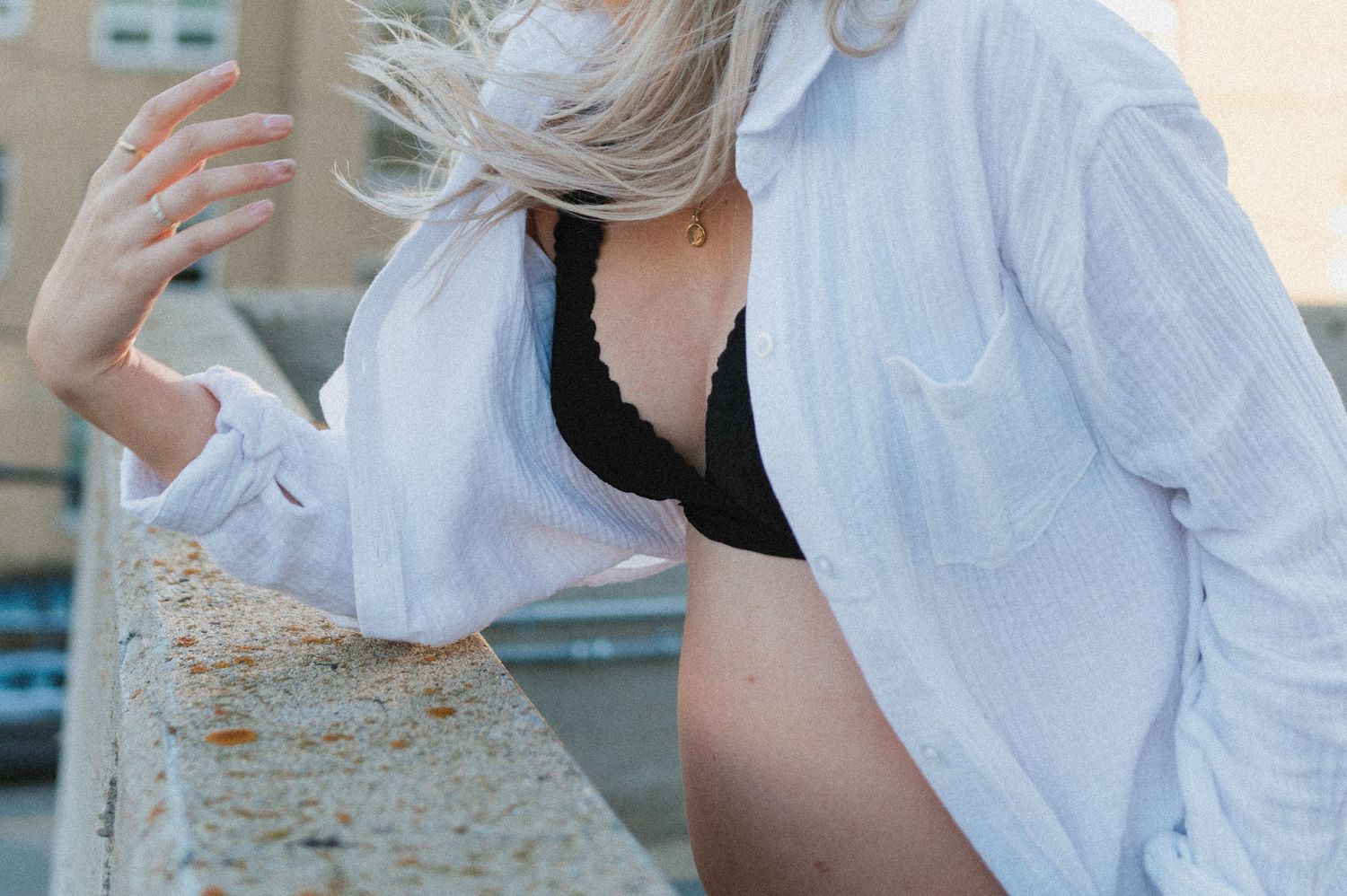 A casual maternity photo featuring a white button-down shirt and black bralette.