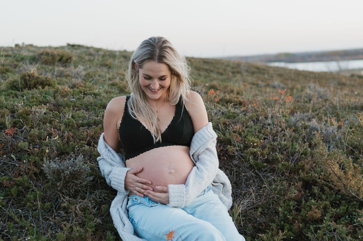 A peaceful maternity moment captured on a hilltop with water view in background.