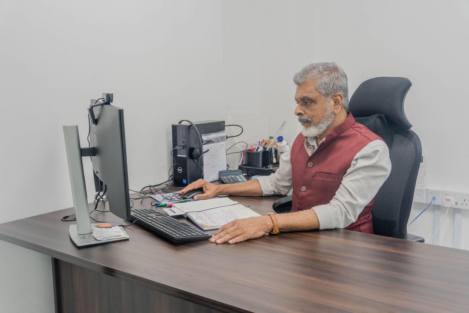 Professional working at wooden desk with dual monitor computer setup in modern office.