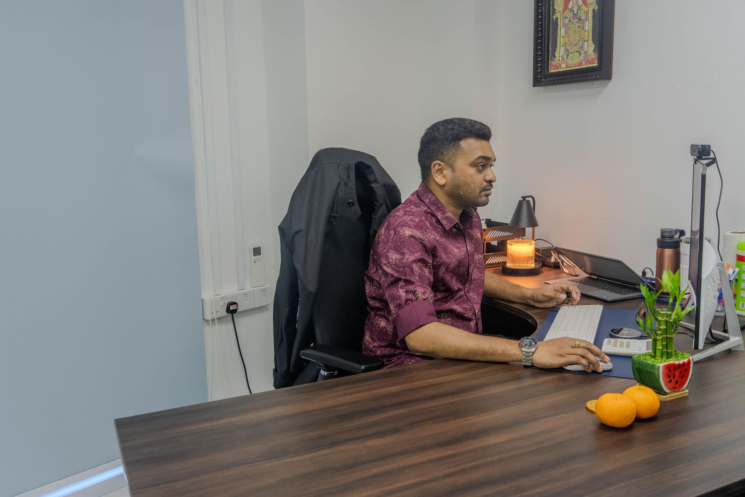 Person working at a desk with colorful decorative items in an office setting.