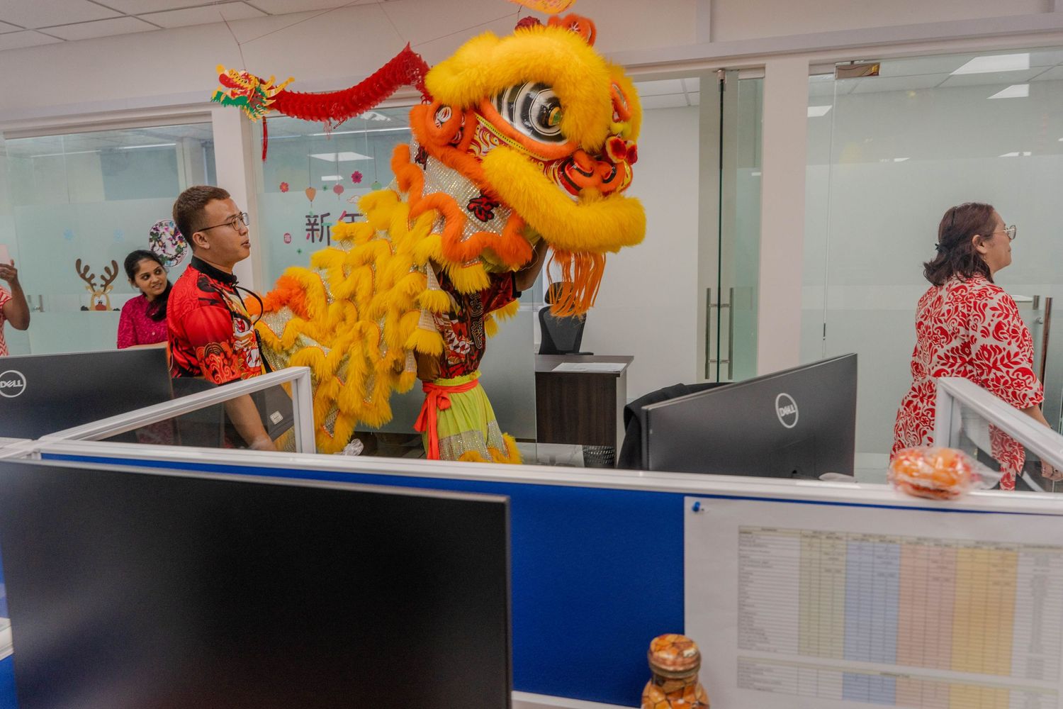 Traditional yellow lion dance costume performance between office cubicles.