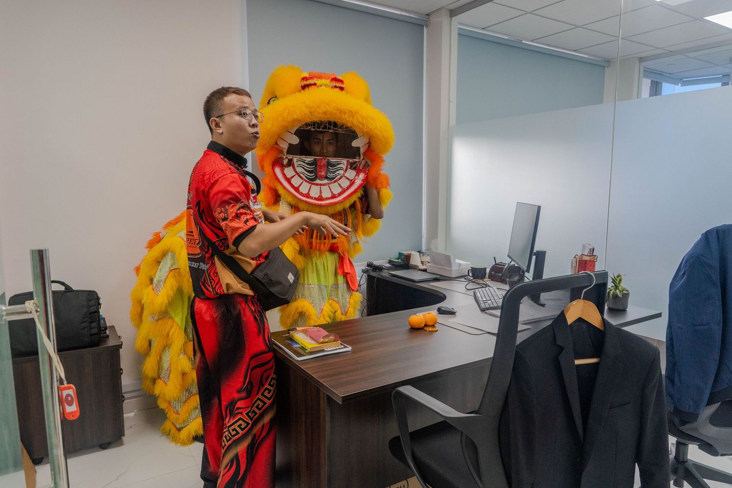 Yellow lion dance costume being performed around office desks.