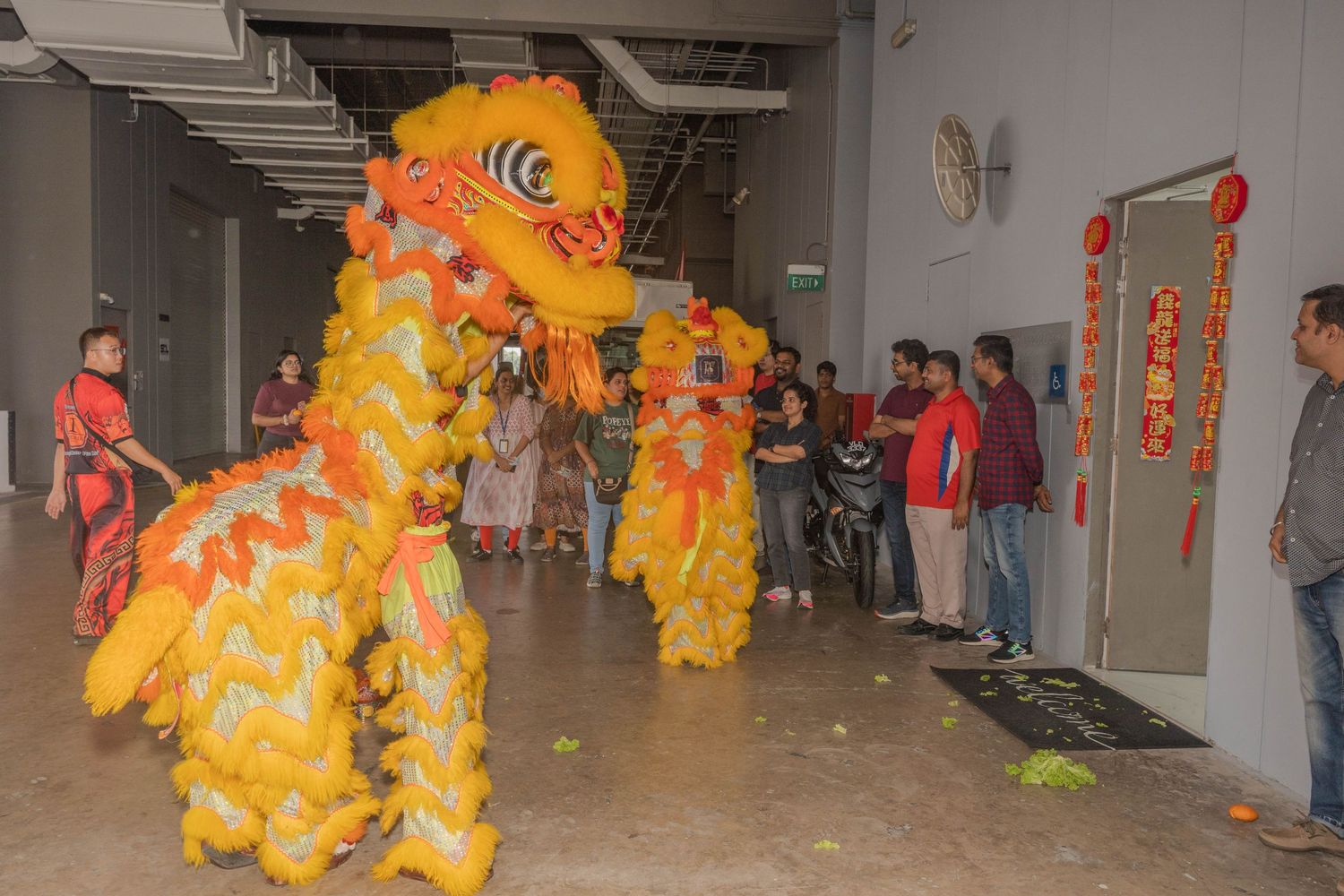 Traditional lion dance performance in an office hallway with spectators.