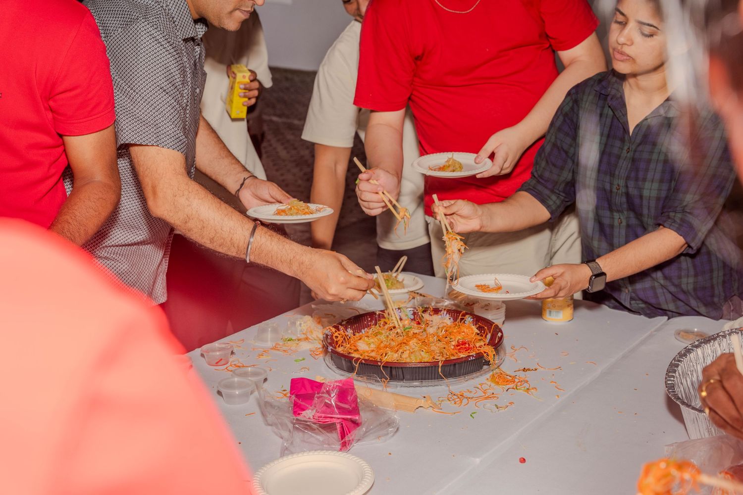Group of people sharing and cutting a celebratory dish at a gathering.