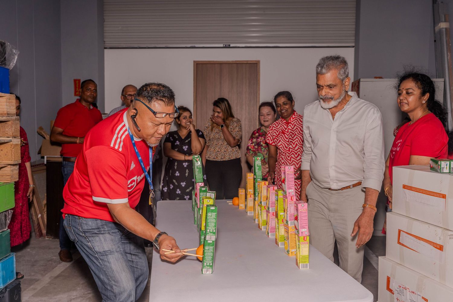 People participating in a team building activity with stacked items in an office space.