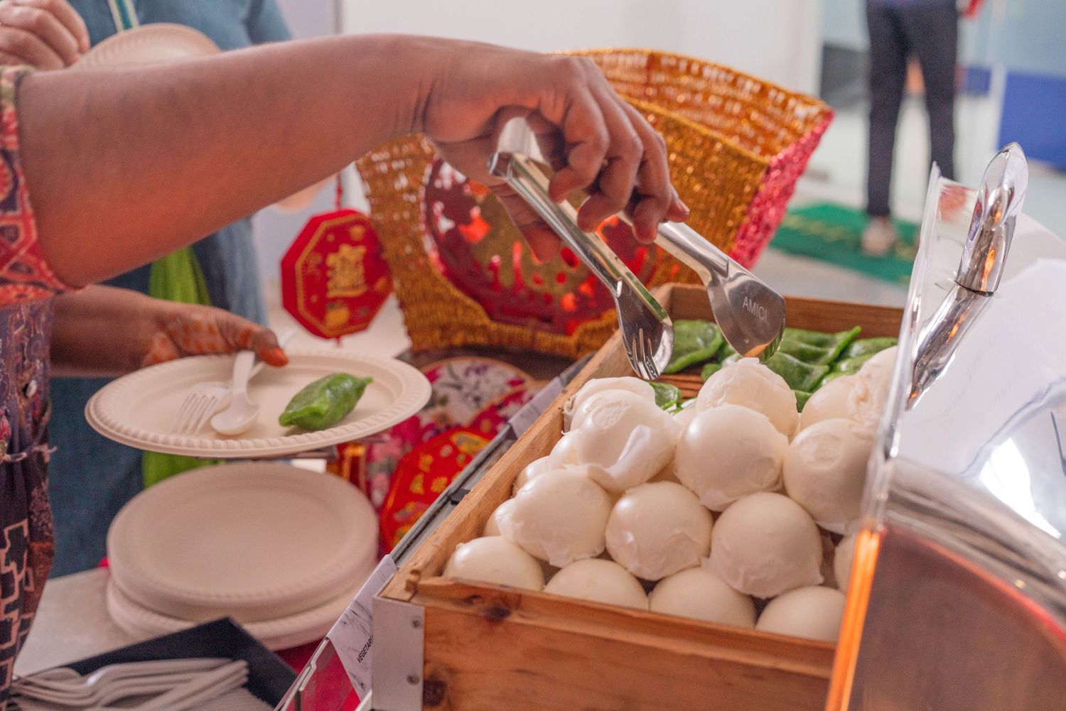 Steamed dumplings being served from a wooden basket at a buffet or restaurant.