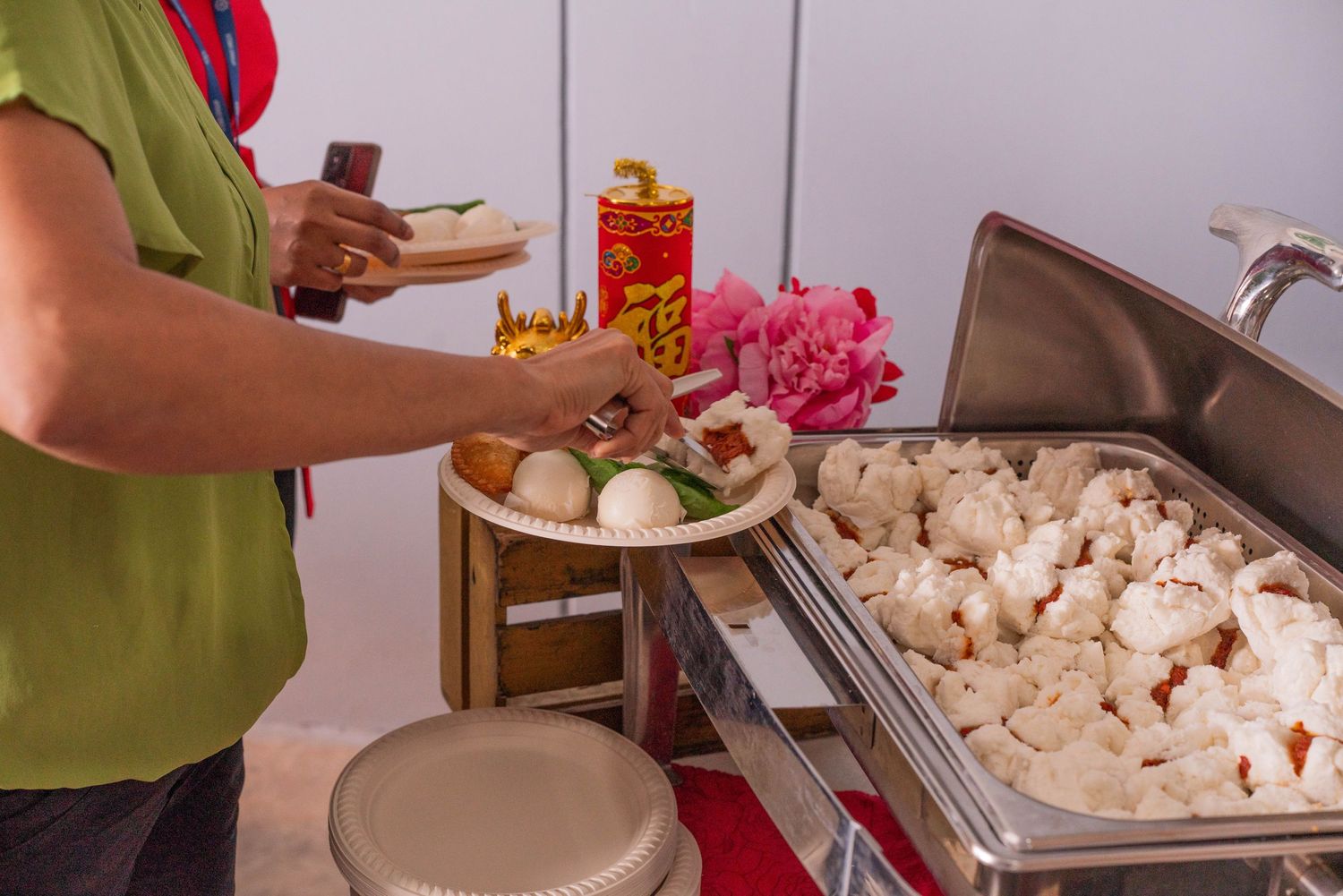 Food service station with steamed dumplings and pink flowers in the background.