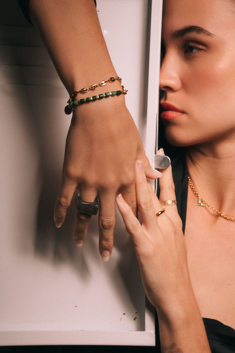 Artistic jewelry photo showcasing beaded bracelets and rings against white background.
