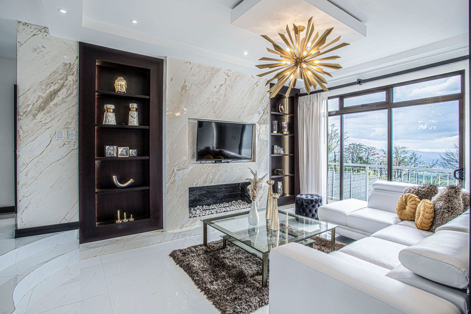 Luxurious open living room featuring contemporary furniture, a decorative shelving unit, and abundant natural light
