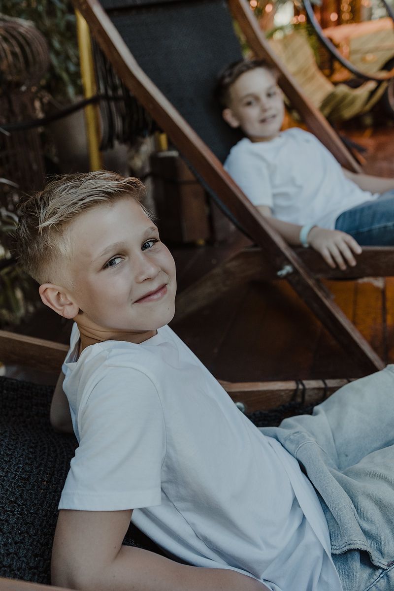 Children sitting on wooden deck chairs during family vacation photoshoot in Playa del Carmen.