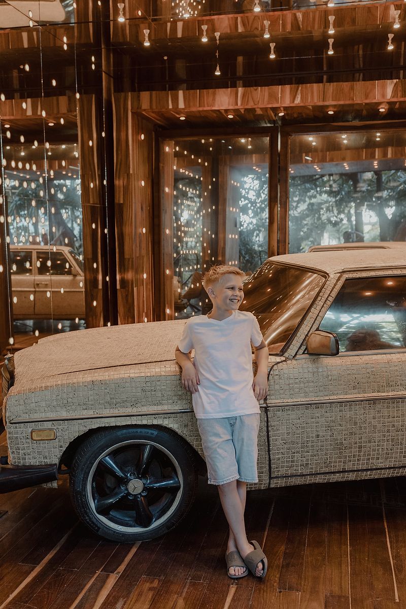 Child leaning on classic car during artistic family portraits at Residencia Art Project, Playa del Carmen.