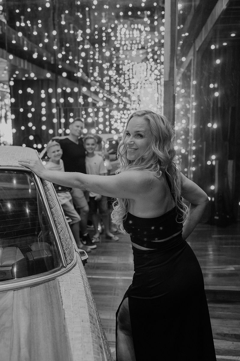 Editorial-style portrait of mother leaning on car with string lights during Playa del Carmen photoshoot.
