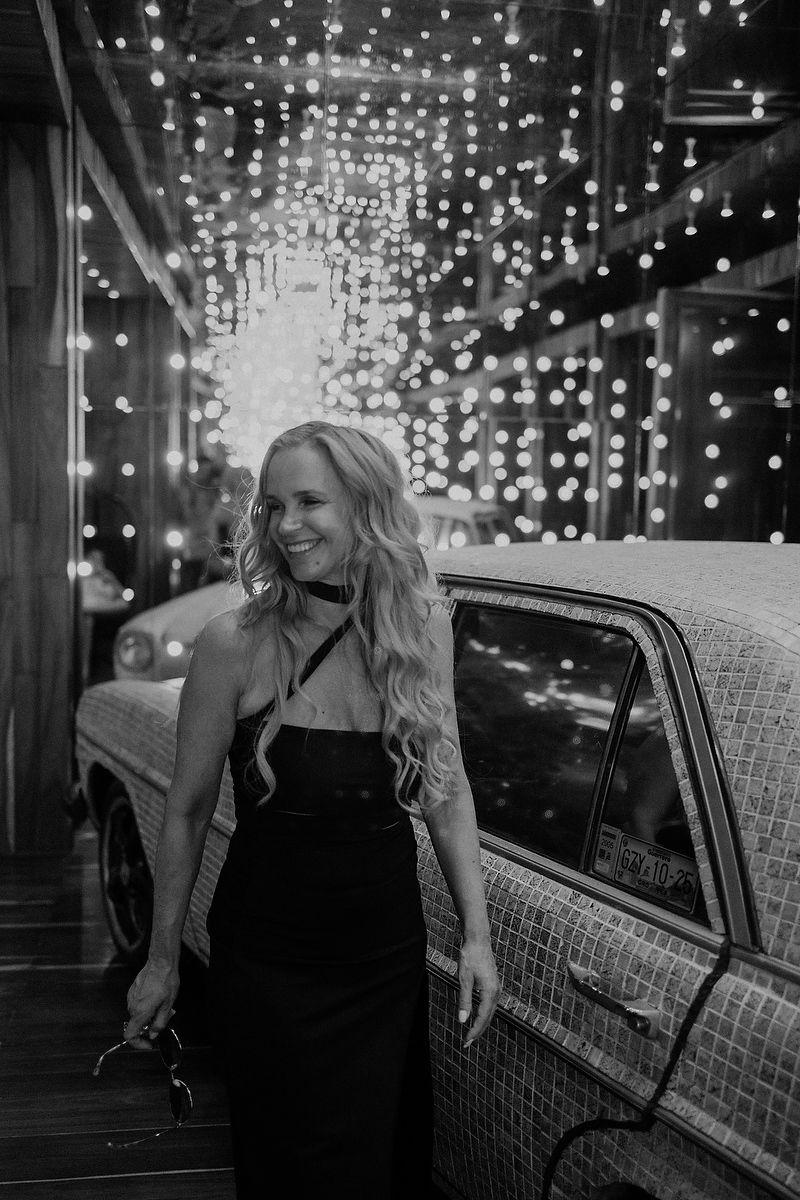 Mother walking past vintage car under string lights during editorial family session in Playa del Carmen.