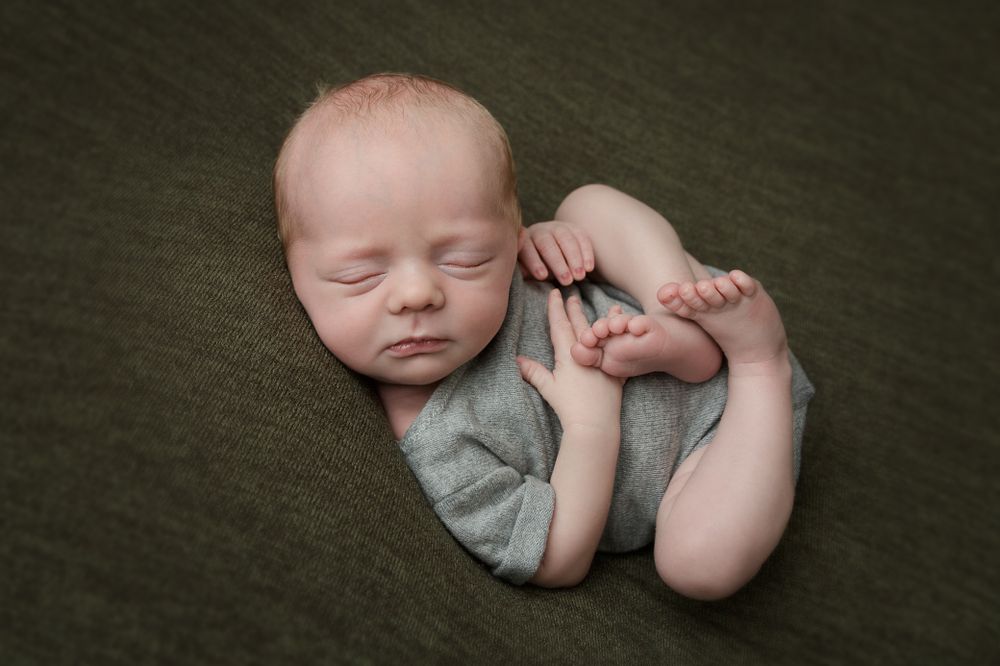 Newborn baby boy peacefully sleeping on a soft green blanket, radiating innocence and tranquility.