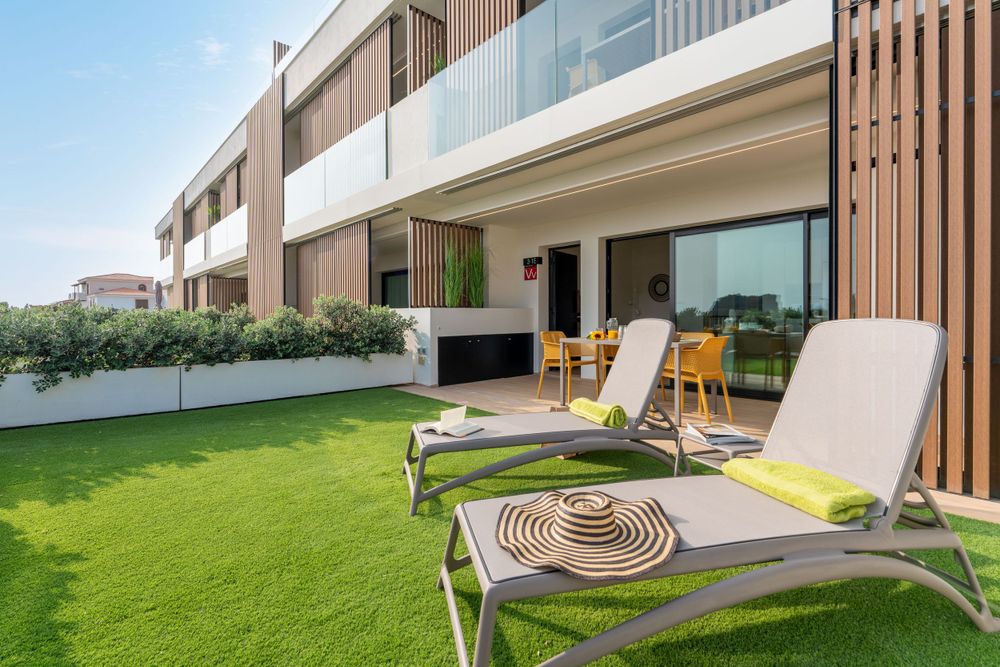 Luxury apartment terrace with loungers on artificial grass and wooden slat facade details.