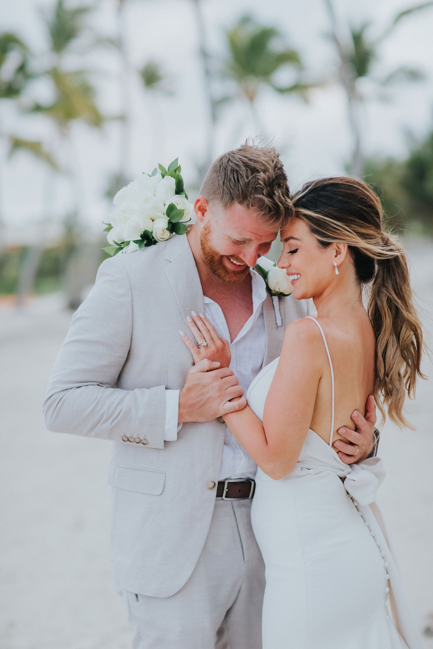 A romantic beachside moment between newlyweds with palm trees in the background.