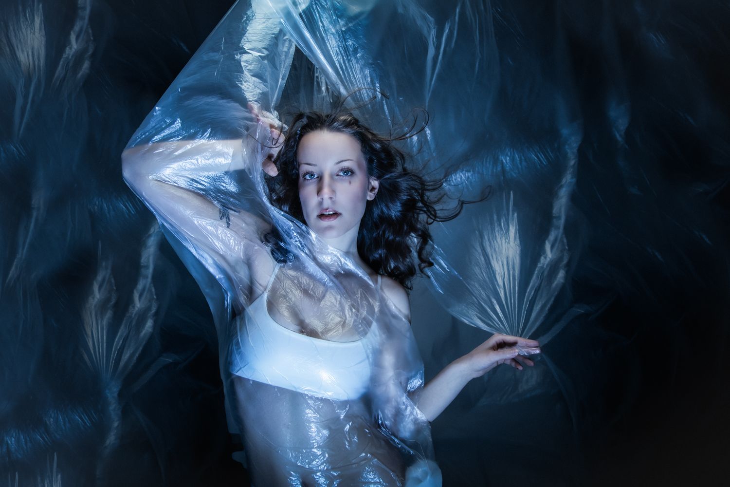 Ethereal portrait in sheer fabric against dark blue background.