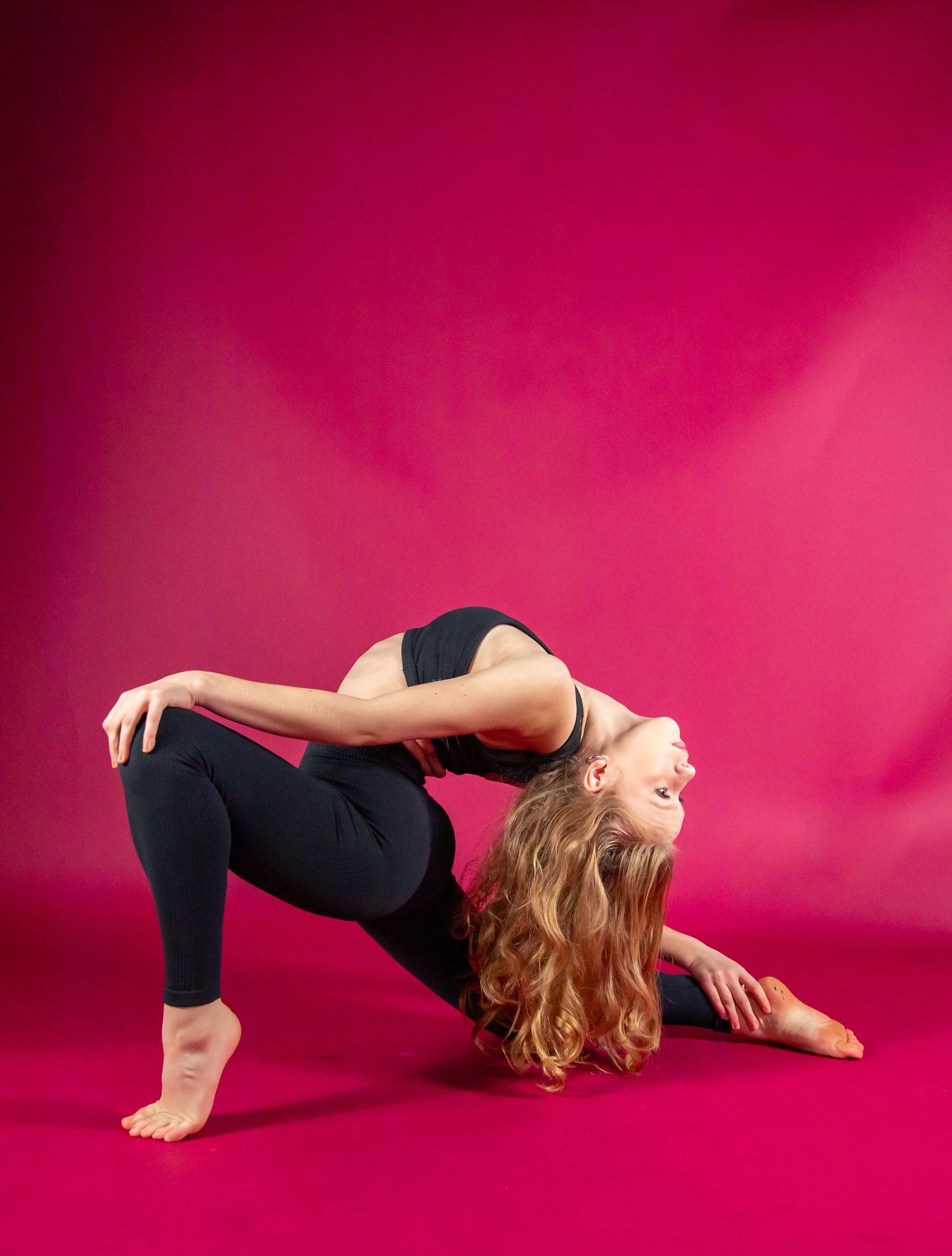 Dancer in black clothing performs flowing movements against vibrant pink backdrop in artistic photo sequence.