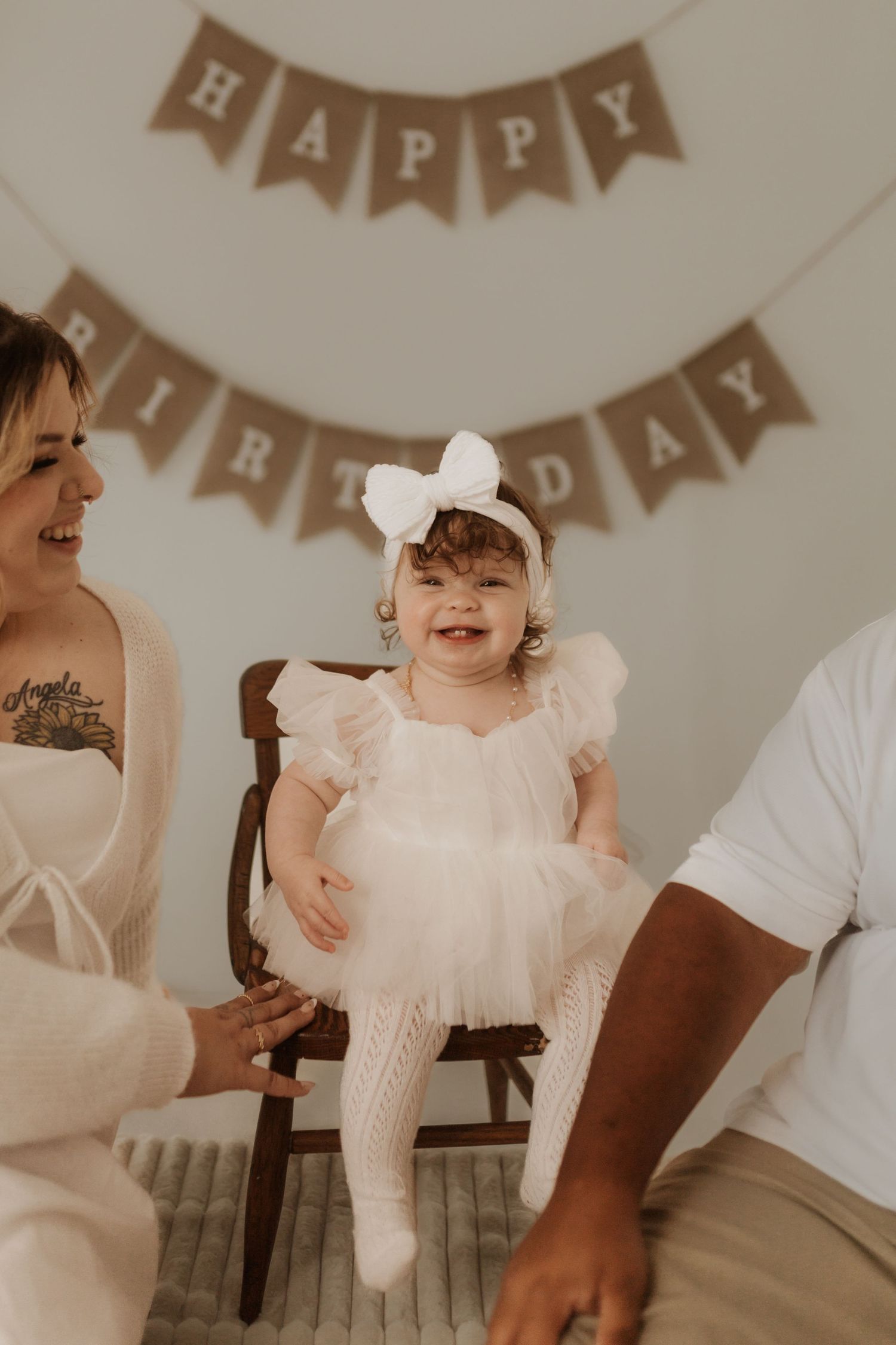 Birthday celebration with 'Happy Birthday' banner and family in white outfits.